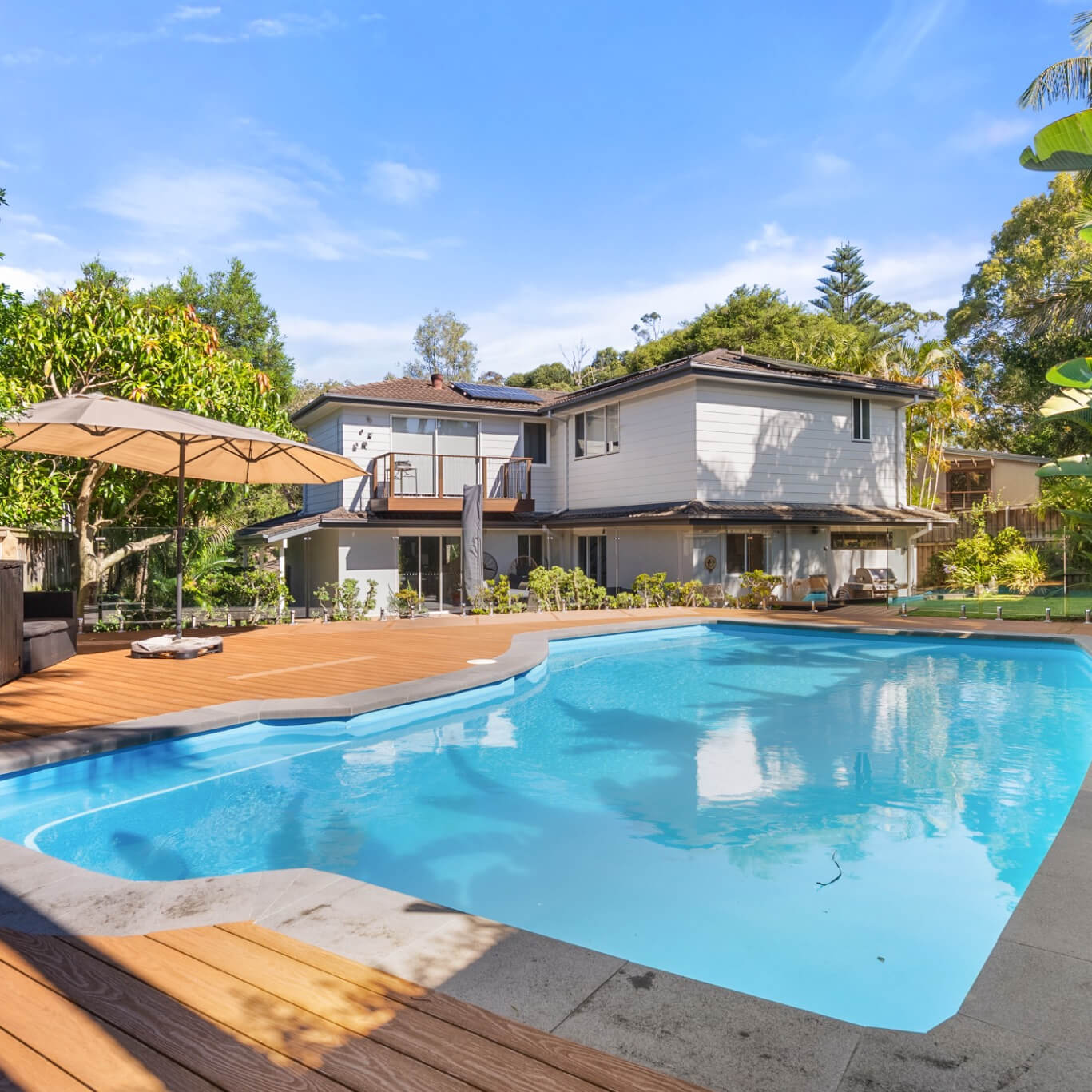 WoodEvo Advanced composite pool deck in Oak surrounding the pool, with the house behind, Mona Vale, by Kovacs Carpentry