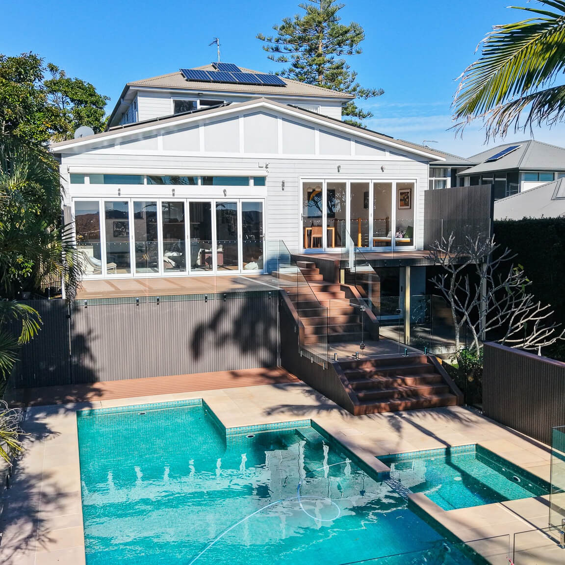 Two-level Trex Transcend Lineage deck in Hatteras with composite stairs, NewTechWood Quick Panel screens and cladding in Silver Grey, and frameless glass balustrades, Dee Why, by Kovacs Carpentry