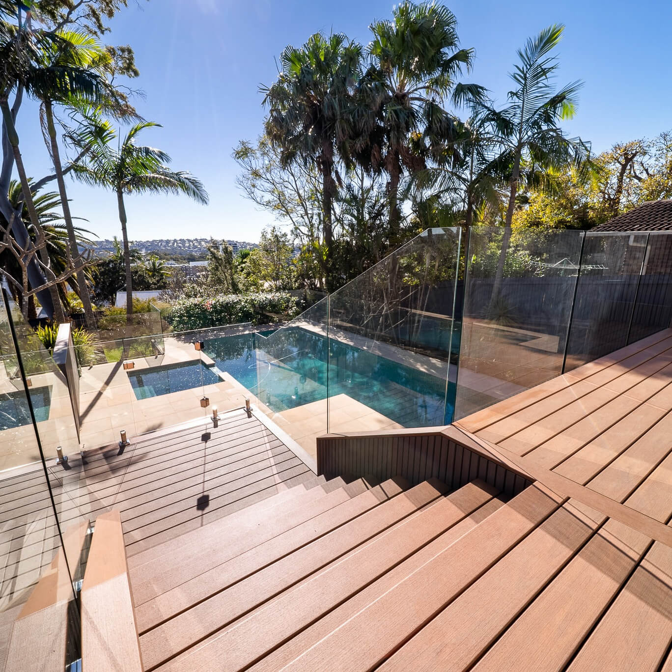 Trex Transcend Lineage deck and stairs in Hatteras with frameless glass balustrades and NewTechWood Quick Panel cladding in Silver Grey, looking down over the pool, Dee Why